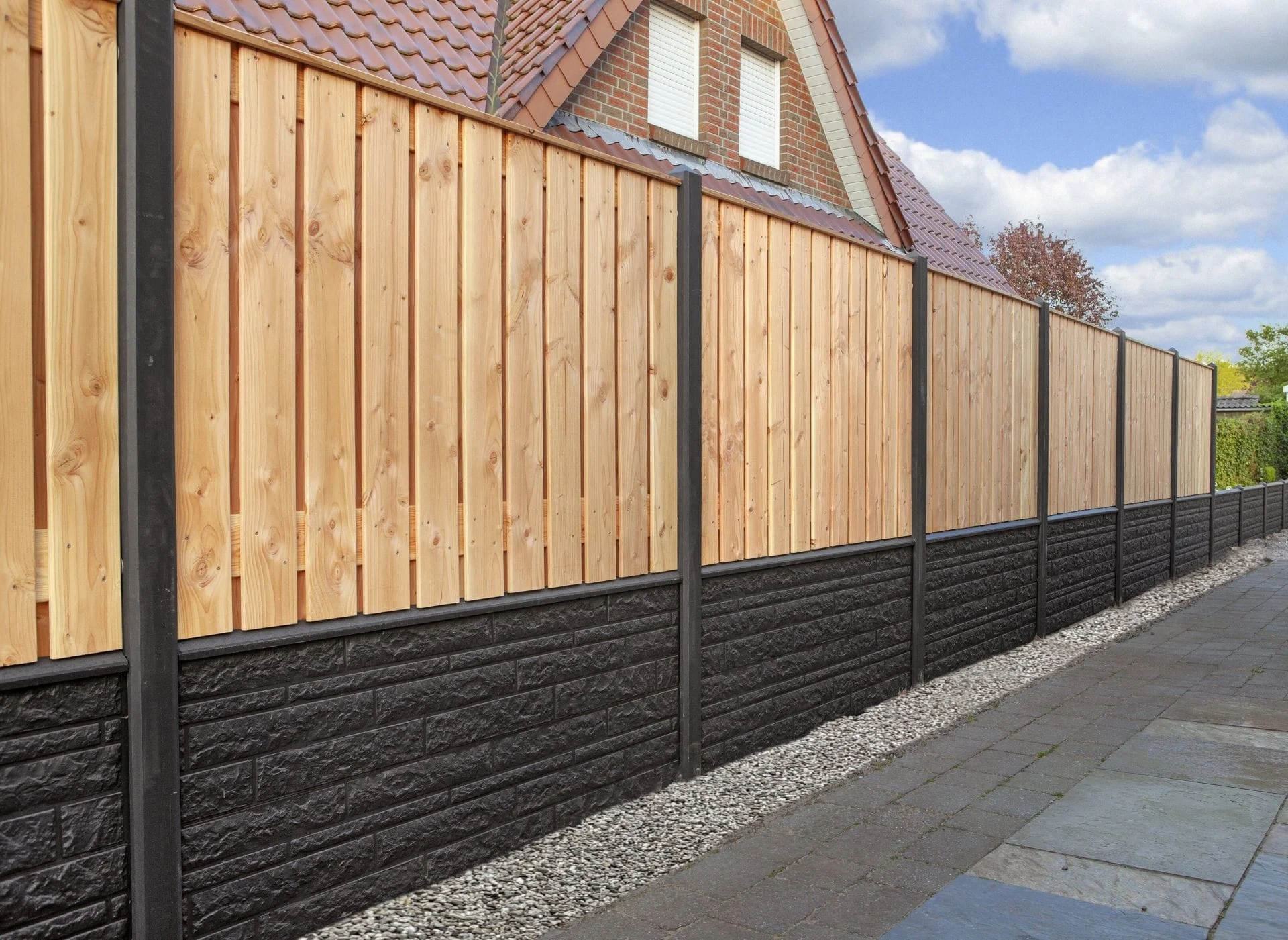 Tuinhout en blokhutten Een duurzame hout-beton schutting met antracietkleurige betonplaten en houten schuttingdelen, geplaatst langs een bestrate tuin met grindafwerking.