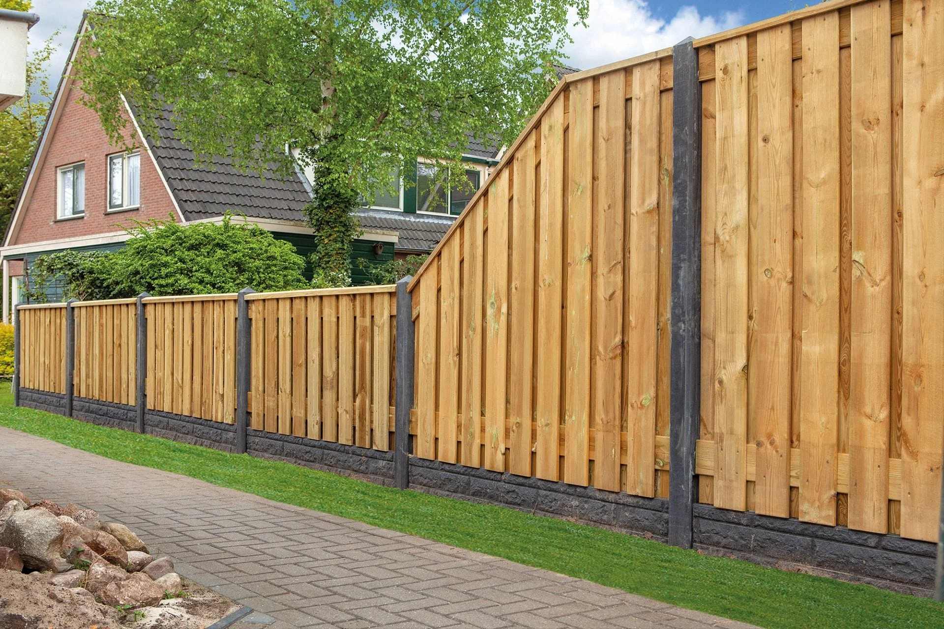 Betonpalen Een houten schutting met betonpalen en een bijpassende tuinpoort, geplaatst in een moderne tuin met bestrating en groene beplanting.