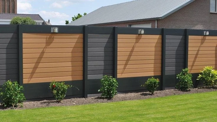 Tuinhout en blokhutten Een stijlvolle Verasol aluminium schutting met houtlook panelen in bruin en antraciet, geplaatst in een moderne tuin met een strak gazon en groene beplanting.