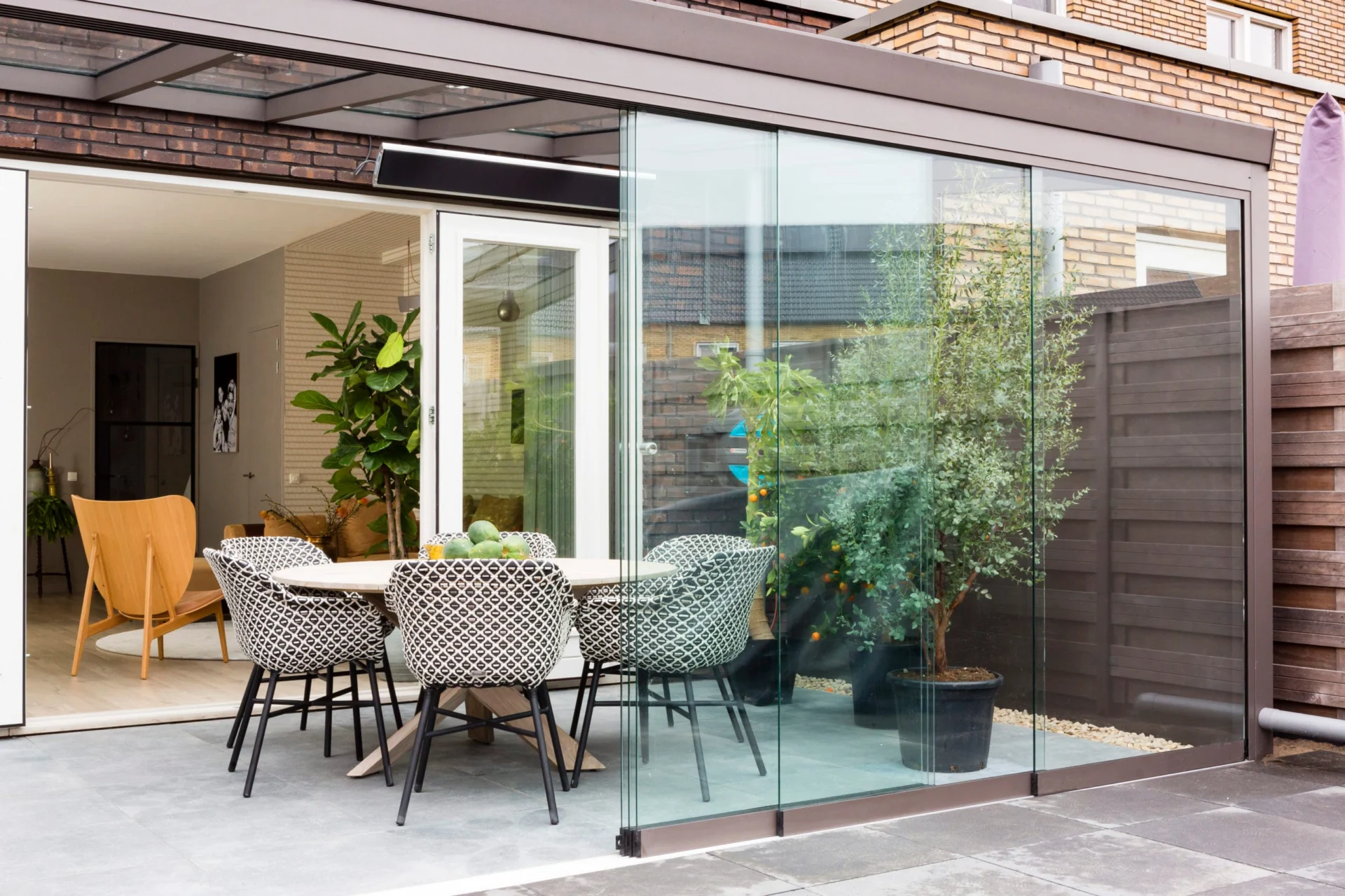 Tuinkamer Profiline tuinkamer in bronskleur, voorzien van glazen schuifwanden en een luxe eethoek. De open verbinding tussen binnen en buiten zorgt voor een ruimtelijke en lichte sfeer.