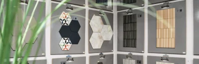 Een wanddisplay met diverse decoratieve en hexagonale wandtegels in verschillende kleuren en patronen, waaronder zwart, wit, groen en terracotta. De tegels hebben zowel moderne als vintage designs.